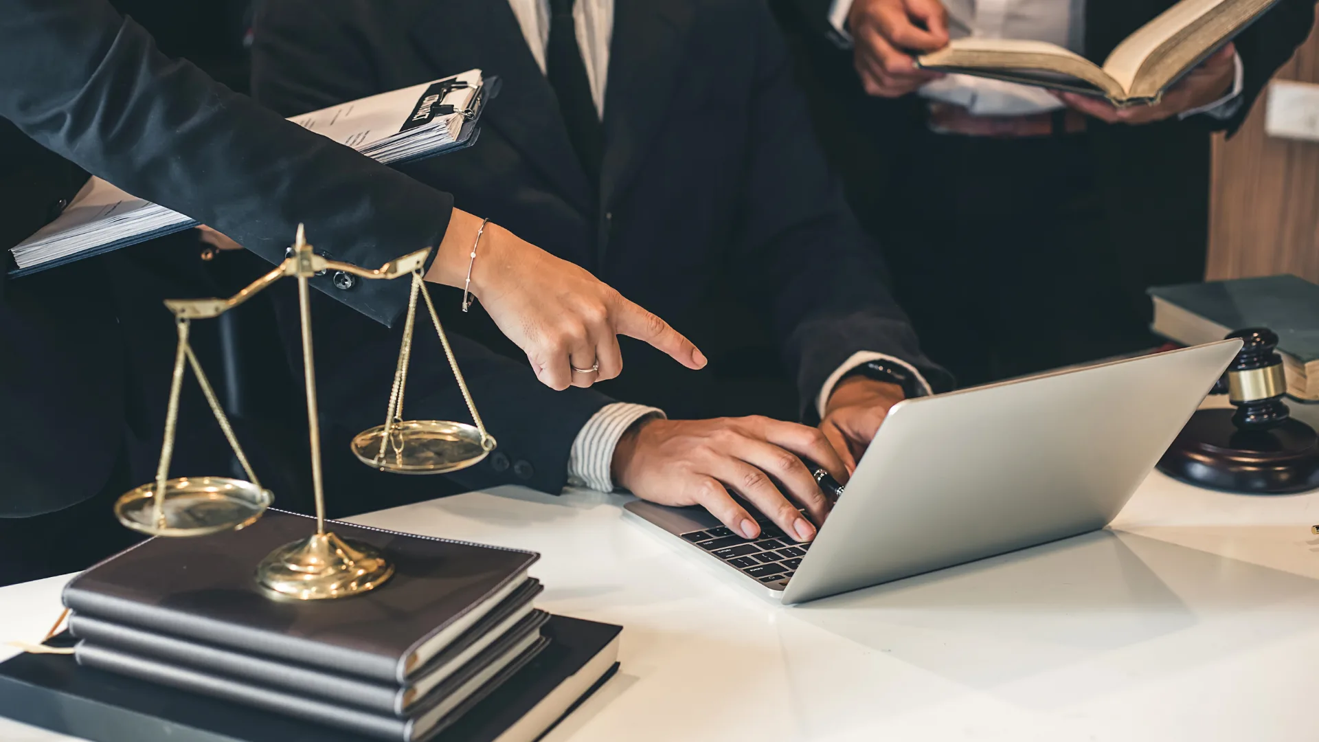 Abogado revisando un caso junto a una balanza de la justicia y su laptop